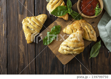 Mini savory meat pies from flaky dough on a wooden board over wooden background. View from above. Copy space. Mini savory meat pies from flaky dough on a wooden board over wooden background. View from above. Copy space. 139799750