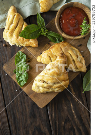 Mini savory meat pies from flaky dough on a wooden board over wooden background. View from above. Copy space. 139799752