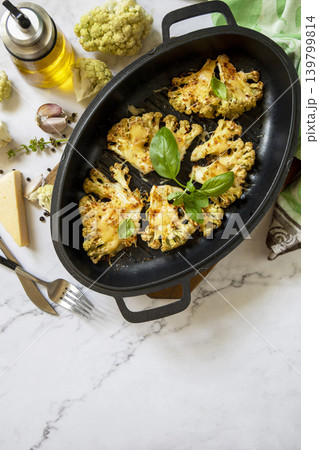 Baked cauliflower keto steaks with cheese on a stone table. Vegetarian cauliflower parmesan. Healthy eating, plant-based meat substitute concept. View from above. Copy space. Baked cauliflower keto steaks with cheese on a stone table. Vegetarian cauliflower parmesan. Healthy eating, plant-based meat substitute concept. View from above. Copy space. 139799814
