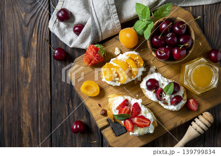 Assorted bruschetta with ricotta, honey, cherries, apricot and strawberry on a rustic table. Berries toast summer breakfast, healthy food. View from above. Copy space. Assorted bruschetta with ricotta, honey, cherries, apricot and strawberry on a rustic table. Berries toast summer breakfast, healthy food. View from above. Copy space. 139799834