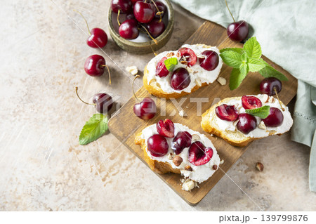 Bruschetta with ricotta, cherry and nuts on a stone tabletop. Berries toast summer breakfast, healthy food. Copy space. Bruschetta with ricotta, cherry and nuts on a stone tabletop. Berries toast summer breakfast, healthy food. Copy space. 139799876