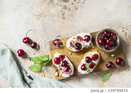 Bruschetta with ricotta, cherry and nuts on a stone tabletop. Berries toast summer breakfast, healthy food. View from above. Copy space. 139799878
