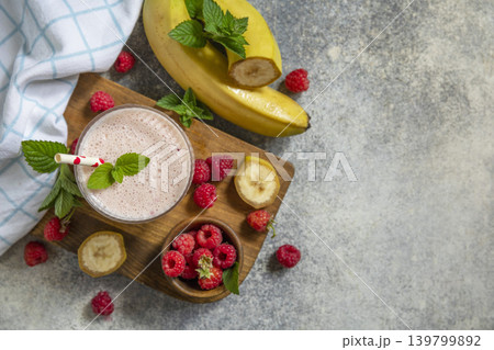 Pink raspberries and banana fruit smoothie or milk protein shake on stone tabletop. Yogurt cocktail, natural detox. Liquid ice cream. View from above. Copy space. Pink raspberries and banana fruit smoothie or milk protein shake on stone tabletop. Yogurt cocktail, natural detox. Liquid ice cream. View from above. Copy space. 139799892