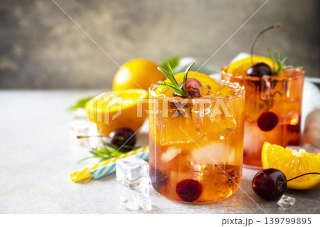 Refreshing summer cherry and orange cocktail cola lemonade or mojito cocktail in glass with ice and mint on stone tabletop. Copy space. 139799895