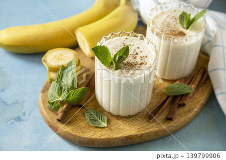 Vegan banana smoothies with cinnamon in drinking glass on a blue stone background. Detox menu, refreshing summer drink. 139799906