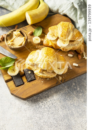 French pastry, freshly baked croissants with peanut butter and banana on a grey stone background. Healthy food dessert concept. Copy space. French pastry, freshly baked croissants with peanut butter and banana on a grey stone background. Healthy food dessert concept. Copy space. 139799939
