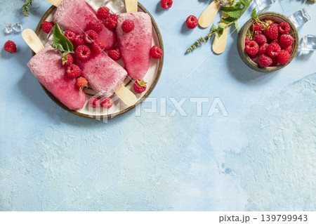 Healthy summer food concept, homemade raspberry ice cream. Vegan raspberry milk popsicles on a blue stone background. View from above. Copy space. Healthy summer food concept, homemade raspberry ice cream. Vegan raspberry milk popsicles on a blue stone background. View from above. Copy space. 139799943