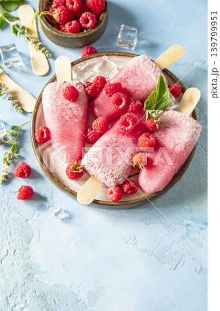 Healthy summer food concept, homemade raspberry ice cream. Vegan raspberry milk popsicles on a blue stone background. Copy space. 139799951
