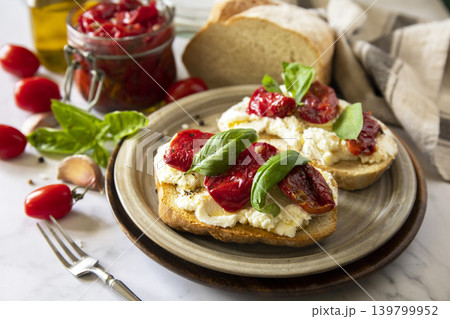 Open sandwiches or bruschetta with cream cheese and sun dried tomatoes on a stone table. Healthy food. Delicious breakfast or wine snack. Open sandwiches or bruschetta with cream cheese and sun dried tomatoes on a stone table. Healthy food. Delicious breakfast or wine snack. 139799952