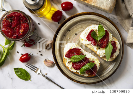 Open sandwiches or bruschetta with cream cheese and sun dried tomatoes on a stone table. Healthy food. Delicious breakfast or wine snack. View from above. 139799959