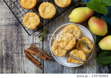 Homemade biscuit cakes sweet cottage cheese muffins with pear, cinnamon on a rustic wooden tabletop. Autumn vegetarian baking. View from above. Copy space. Homemade biscuit cakes sweet cottage cheese muffins with pear, cinnamon on a rustic wooden tabletop. Autumn vegetarian baking. View from above. Copy space. 139799968