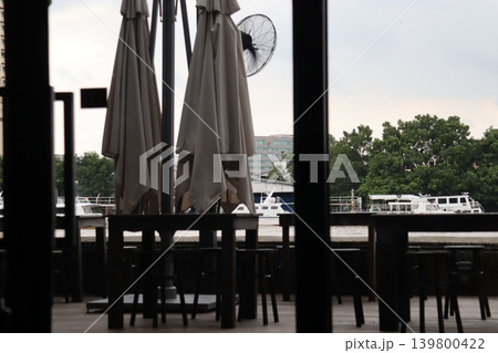 Riverfront Cafe Seating with Umbrellas and Boats Riverfront Cafe Seating with Umbrellas and Boats 139800422