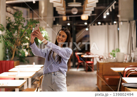 Young woman taking selfie with smartphone in restaurant 139802494