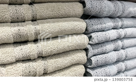 Neat stacks of soft beige and blue terry towels with woven patterns for modern bathroom styling 139803758