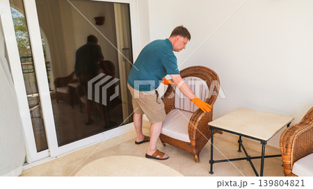 A man rearranges furniture, moves a chair to a new location 139804821