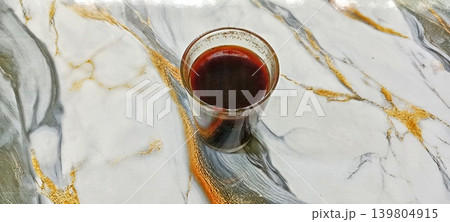 A glass of coffee on a gold-patterned marble floor A glass of coffee on a gold-patterned marble floor 139804915