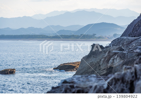 荒々しい岩肌の海岸線と遠くに霞む山々の風景 荒々しい岩肌の海岸線と遠くに霞む山々の風景 139804922