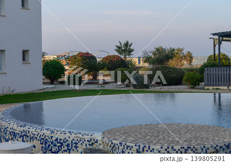 Refreshing tranquility by the shimmering pool amid lush greenery and serene landscape at dusk 139805291