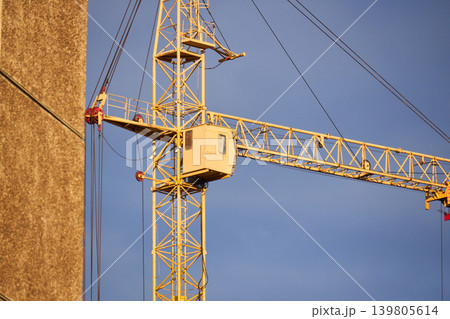 Orange tower crane jib with trolley and pulleys in action Orange tower crane jib with trolley and pulleys in action 139805614