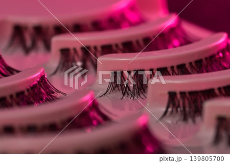 Lash display scene. Eyelash trays under vibrant neon illumination. Luxurious lash presentation using colorful ambient lighting effects Lash display scene. Eyelash trays under vibrant neon illumination. Luxurious lash presentation using colorful ambient lighting effects 139805700