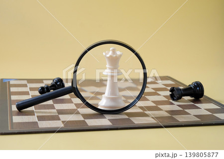 Chess pieces is viewed through a magnifying glass. 139805877