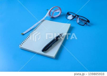 A book note with measuring tape ,pen on background. A book note with measuring tape ,pen on background. 139805910