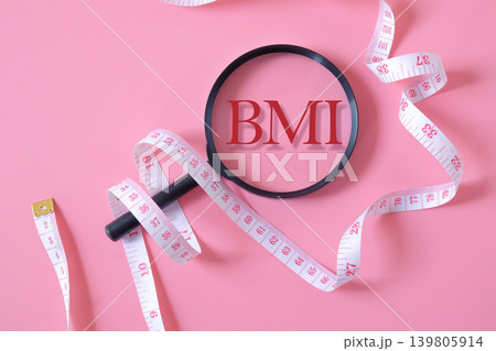 BMI text on magnifying glass with measuring tape. 139805914