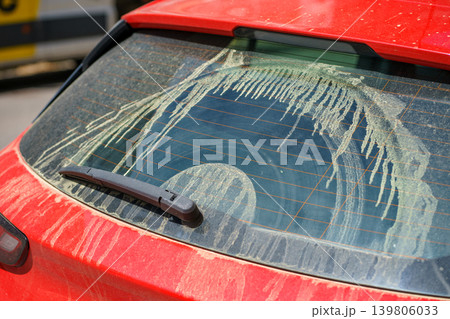 Rear car window covered with thick pollen streaks, intense spring bloom causing allergies, environmental exposure and seasonal health concept. 139806033