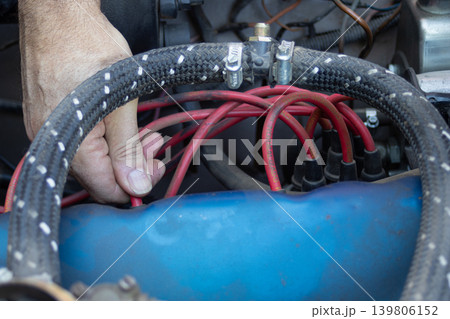 Mechanic diagnosing car engine ignition wires Mechanic diagnosing car engine ignition wires 139806152