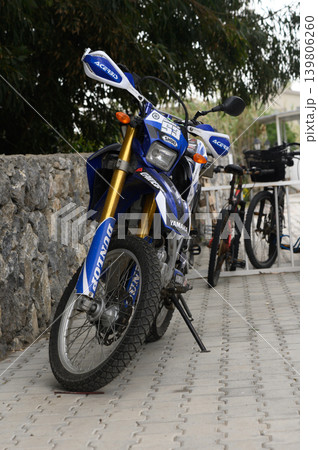 Gaziveren Cyprus -03.04.2025 Motorbike resting beside a stone wall in a sunny outdoor setting showcasing adventure and freedom Gaziveren Cyprus -03.04.2025 Motorbike resting beside a stone wall in a sunny outdoor setting showcasing adventure and freedom 139806260