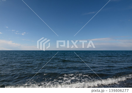 Endless blue horizon meets tranquil waves under a clear sky at midday by the coast 139806277