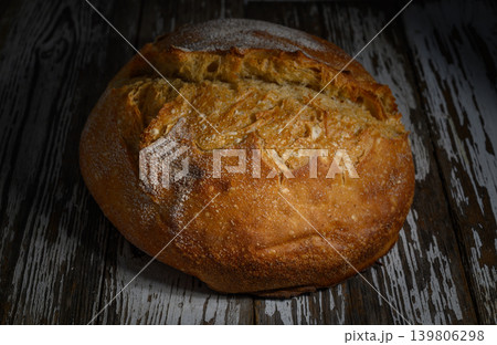 Freshly baked artisanal bread resting on a rustic wooden surface in a cozy Freshly baked artisanal bread resting on a rustic wooden surface in a cozy 139806298