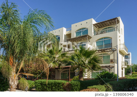 Serene afternoon at a coastal resort with palm trees and luxurious balconies in a sunlit paradise. Serene afternoon at a coastal resort with palm trees and luxurious balconies in a sunlit paradise. 139806340
