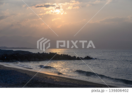Golden sunset washes over tranquil shoreline as waves softly lap on sandy beach 139806402