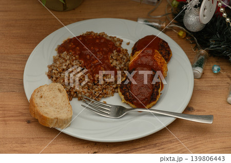 Delicious homemade meal featuring savory meat patties and hearty buckwheat served on a cozy wooden table Delicious homemade meal featuring savory meat patties and hearty buckwheat served on a cozy wooden table 139806443
