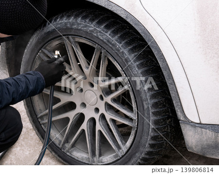 Man inflating dirty car tire. Driver checks air pressure. Auto service maintenance, transportation safety, road trip concept. 139806814
