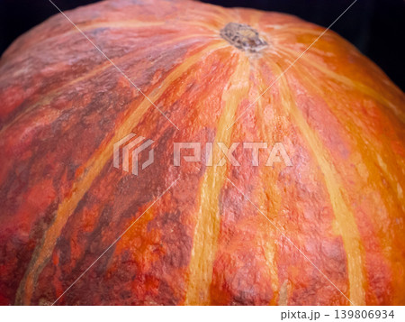Close up of an orange pumpkin skin surface with visible texture and stem. Autumn harvest decoration concept for fall season and Halloween. Close up of an orange pumpkin skin surface with visible texture and stem. Autumn harvest decoration concept for fall season and Halloween. 139806934