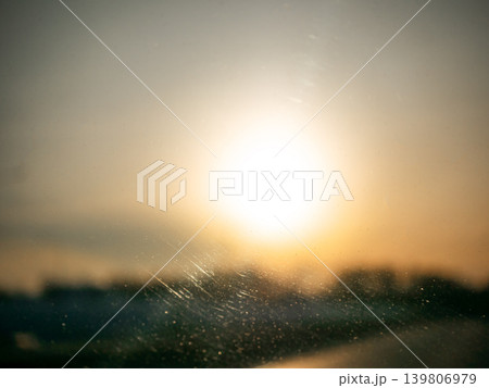 Bright sun shining through a dirty windshield at sunrise. Golden hour light and abstract dirty glass for background texture. Bright sun shining through a dirty windshield at sunrise. Golden hour light and abstract dirty glass for background texture. 139806979