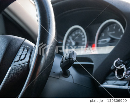 Black steering wheel with buttons and dashboard gauges inside a modern car interior. Vehicle driving experience for automotive journey. Black steering wheel with buttons and dashboard gauges inside a modern car interior. Vehicle driving experience for automotive journey. 139806990