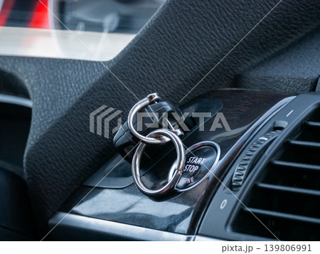 Car remote starter key fob attached to push button start stop engine button. Modern vehicle ignition system and comfort of smart key. 139806991