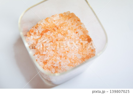 Pink Himalayan salt in a glass container. Mineral seasoning for cooking and health. Natural ingredient for spa and organic wellness lifestyle. Food background with coarse raw crystal. Pink Himalayan salt in a glass container. Mineral seasoning for cooking and health. Natural ingredient for spa and organic wellness lifestyle. Food background with coarse raw crystal. 139807025