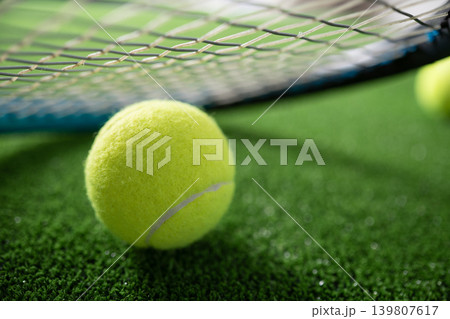 Close up tennis ball near racket on green court grass Close up tennis ball near racket on green court grass 139807617