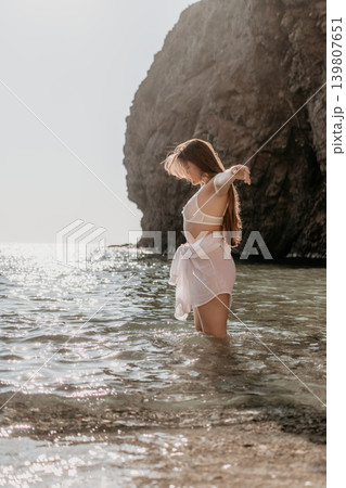 Woman beach ocean enjoys a peaceful summer moment standing in sparkling turquoise water against majestic coastal cliffs Woman beach ocean enjoys a peaceful summer moment standing in sparkling turquoise water against majestic coastal cliffs 139807651