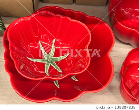 Red ceramic tomato shaped bowls and plate stacked on wooden surface Red ceramic tomato shaped bowls and plate stacked on wooden surface 139807839