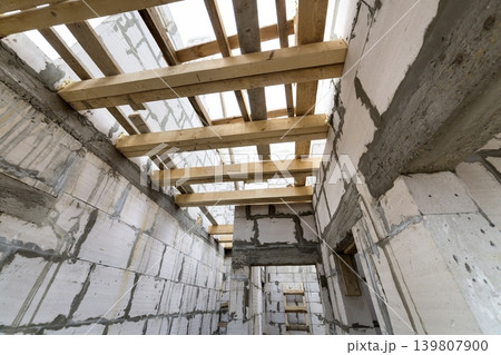 House room interior under construction and renovation. Energy saving walls of hollow foam insulation blocks, wooden ceiling beams and roof frame. House room interior under construction and renovation. Energy saving walls of hollow foam insulation blocks, wooden ceiling beams and roof frame. 139807900