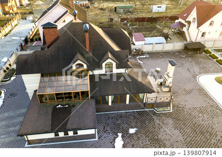 Aerial top view of new residential house cottage with shingle roof on fenced big yard on sunny day. Aerial top view of new residential house cottage with shingle roof on fenced big yard on sunny day. 139807914