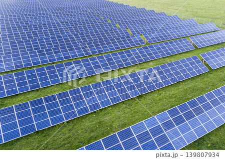 Large field of solar photo voltaic panels system producing renewable clean energy on green grass background. Large field of solar photo voltaic panels system producing renewable clean energy on green grass background. 139807934