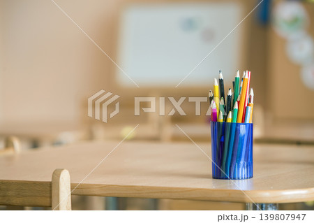 Wooden colorful drawing pencils arranged in plastic jug on light copy space background. Wooden colorful drawing pencils arranged in plastic jug on light copy space background. 139807947
