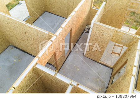 Construction of new and modern modular house. Walls made from composite wooden sip panels with styrofoam insulation inside. Building new frame of energy efficient home concept. Construction of new and modern modular house. Walls made from composite wooden sip panels with styrofoam insulation inside. Building new frame of energy efficient home concept. 139807964