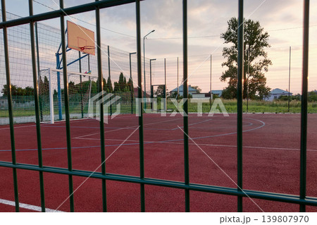 Outdoors mini football and basketball court with ball gate and basket surrounded with high protective fence. Outdoors mini football and basketball court with ball gate and basket surrounded with high protective fence. 139807970